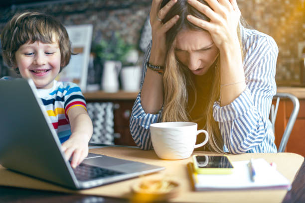 istock Mother working from home and online education with kid. Stressed with computer and phone. Child make noise and disturb woman at work. Homeschooling and freelance job. Smiling Boy playing at kitchen. 1277303675