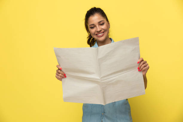 donna casual positiva sorridente e leggendo giornale - newspaper reading holding paper foto e immagini stock