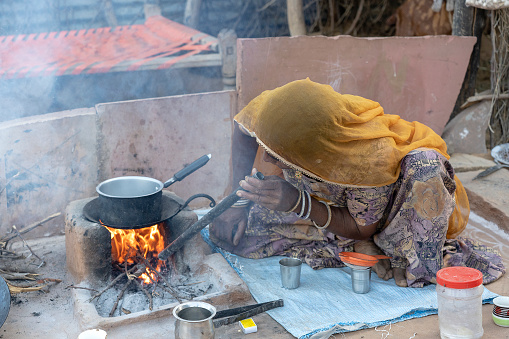 Pushkar, India - nov 13, 2018 : Indian woman making tea for her family in the courtyard near the desert Thar, Rajasthan, India