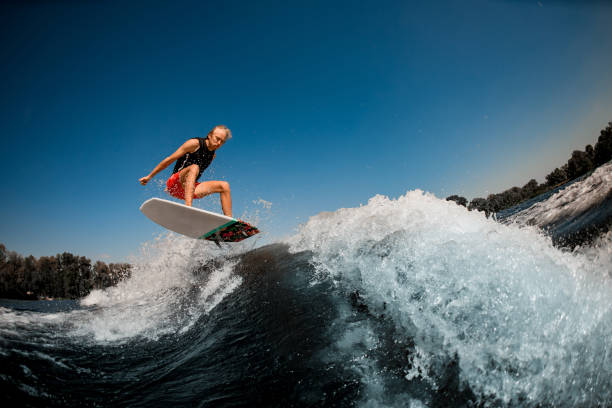 istock man bounces on surf style wakeboard over splashing wave against blue sky 1277308472