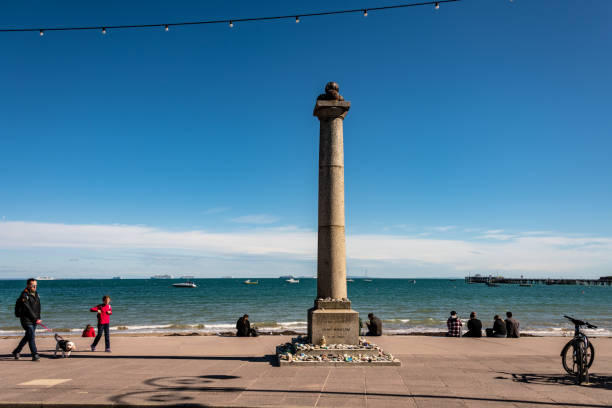Swanage, UK. Saturday 26 September 2020. John Mowlem 1862 Monument on Swanage Seafront as people sit and walk on the beach.