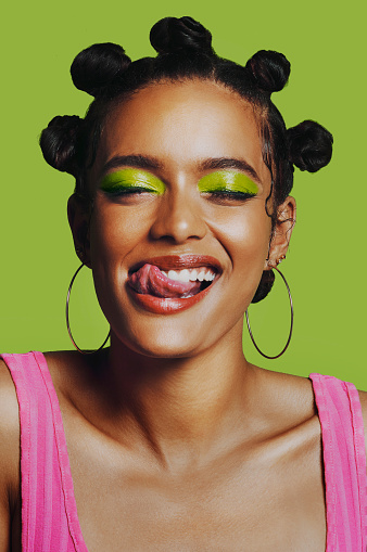 Shot of a woman posing against a green background with her bantu knots