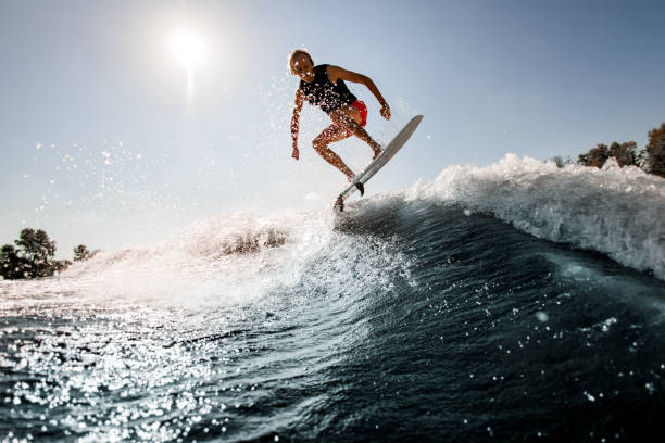 istock view of man jumping over river wave on board against sunny blue sky. 1277309962