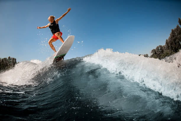 istock great view of man jumping over river wave on board against sunny blue sky. 1277310118
