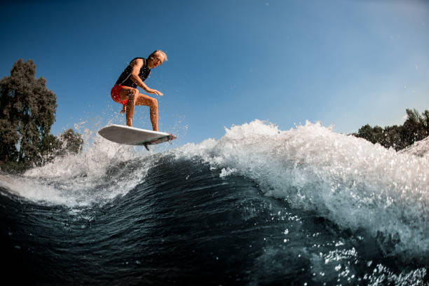 istock Beautiful view of guy on surf style wakeboard masterfully jumping over splashing wave 1277310303