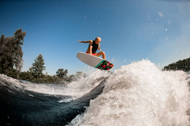 istock active energetic man on surf style wakeboard masterfully jumping over splashing wave 1277310351