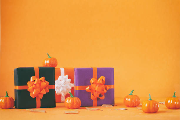 オレンジ色の背景にカボチャとハロウィーンのカラフルなギフトボックス。誕生日、ハロウィーンパーティーのお祝いのコンセプト。