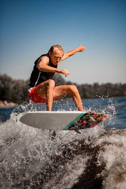 istock close-up view of man on surf style wakeboard masterfully jumping over splashing wave 1277310985