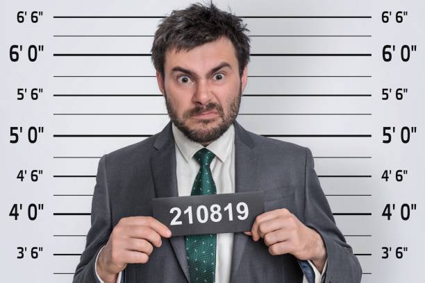 mugshot of man in suit at police station - mug shot imagens e fotografias de stock