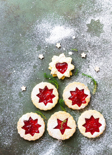 istock Christmas or New Year tree made from Austrian Linzer cookies with jam and dusted with sugar powder on green stone background. Holiday, celebration and cooking concept. 1277311412