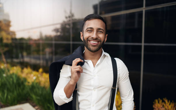 istock Handsome bearded smiling Indian businessman standing with jacket over shoulders 1277312174