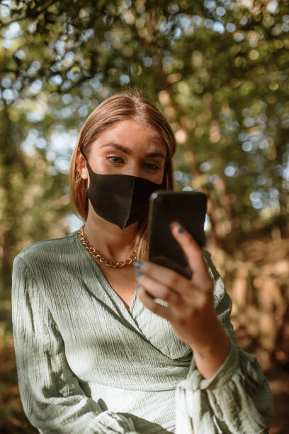 istock Young woman with a protective face mask using a smart phone 1277313394