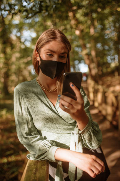 istock Young woman with a protective face mask using a smart phone 1277316373