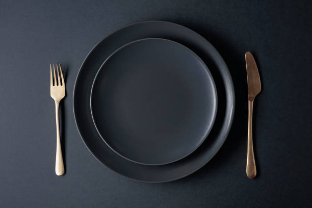 istock Empty black plate, fork and knife on a black background. Top view. 1277316679