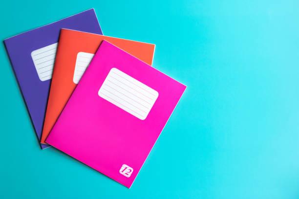istock Colored notebooks in purple, orange, pink colors on a turquoise background 1277319627