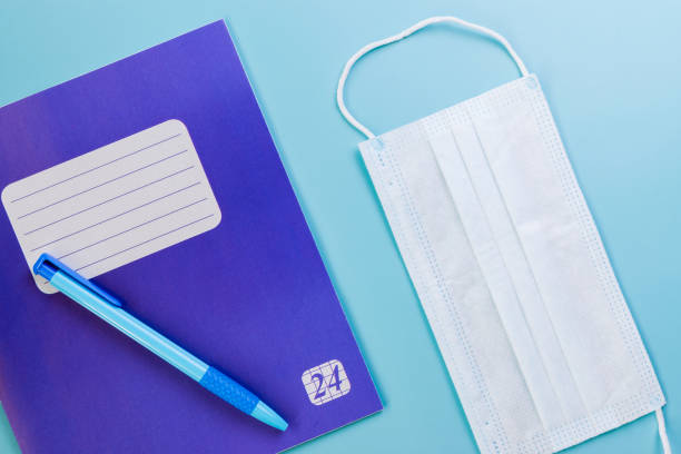 istock Notebook, pen, white medical mask on a pink background. 1277319849