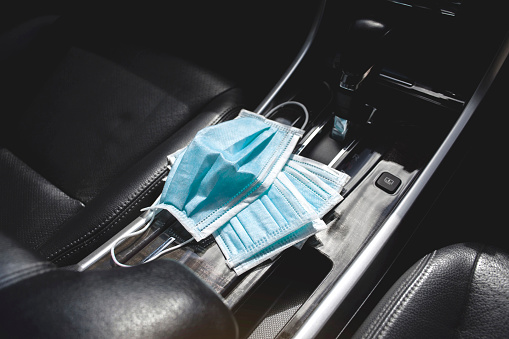 Medical face mask placed on center console inside to the car , Coronavirus (COVID-19) prevention concept