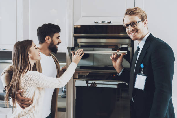 People stand in the kitchen and examine the stove. stock photo