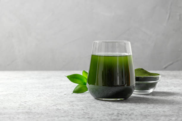 хлорелла здоровый напиток в стекле на сером фоне. - spirulina bacterium superfood healthy lifestyle alternative medicine стоковые фото и изображения