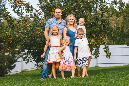 Happy large family with children in garden, apple tree on background.