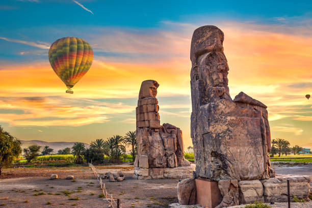 Air balloons and Colossus Hot air balloons and Colossus of Memnon in Luxor at sunrise, Egypt luxor thebes stock pictures, royalty-free photos & images