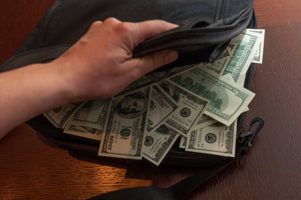 istock A man's hand and a bag with 100 American dollar bills. 1277330446