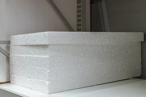 Stacks of thick polystyrene sheets in packaging at a building materials warehouse or in a store. The texture of the insulating sheets in the package. The concept of purchasing materials for building construction and renovation of premises.