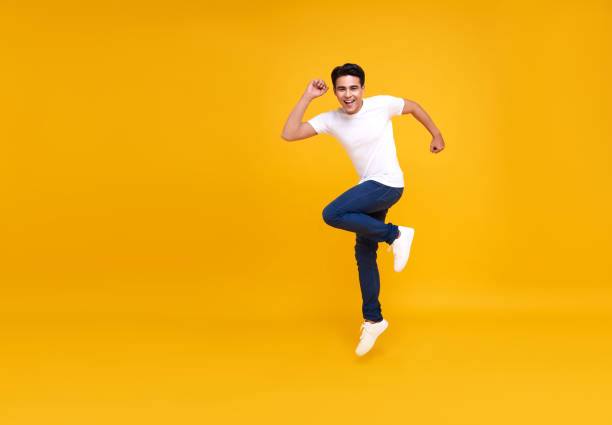 istock Young handsome Asian man smiling and jumping while celebrating success isolated over yellow background. 1277331763