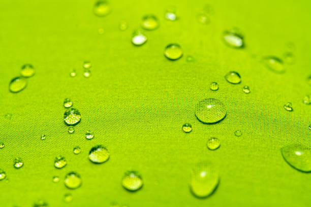 Macro shot of water drop over blue cloth, shows absorption - water repellence of microfiber textile.