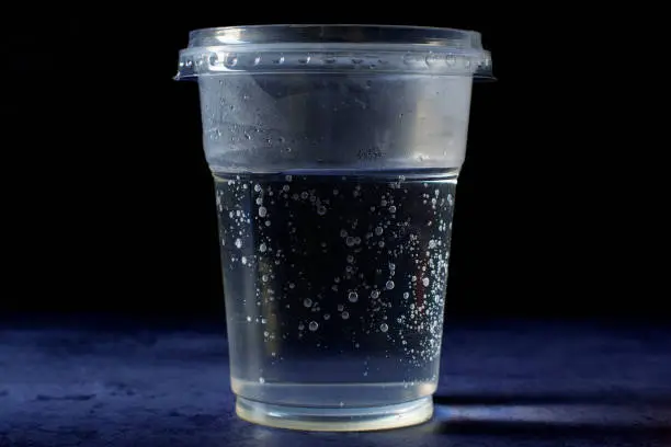 The cup has a plastic lid on it and it is standing on deep blue background.