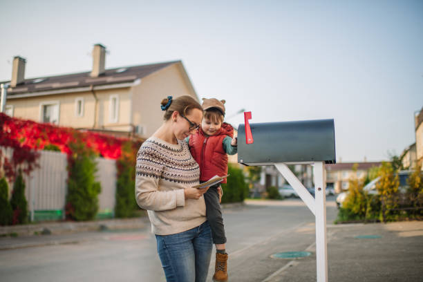 Family sending or receiving mail with mailbox near house Little boy and his mother on a street with mailbox. absentee ballot photos stock pictures, royalty-free photos & images