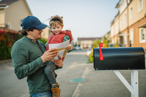 Little boy and his father on a street with mailbox.