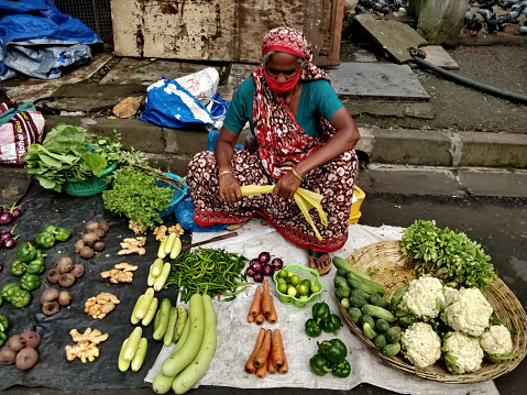 Mumbai, Maharashtra, India - 11 OCTOBER 2020: Woman wearing face mask and selling vegetables in traditional markets in the midst of the Corona virus pandemic.