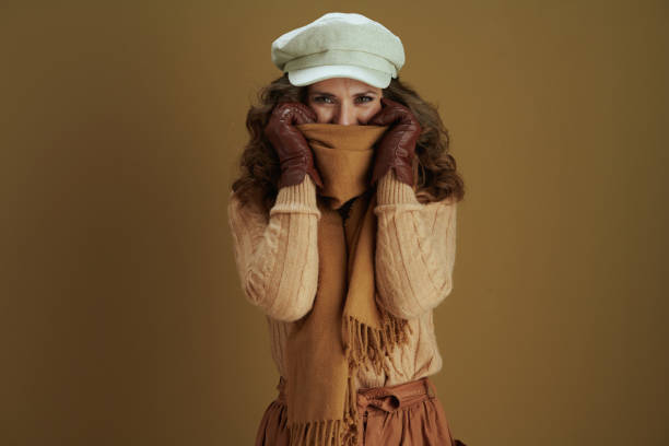 smiling modern woman wrapping in scarf on beige background