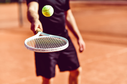 Male Tennis Player Bouncing Ball On Racket