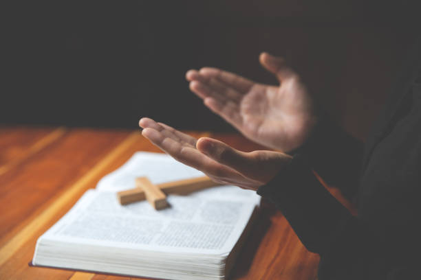 hand der frau beim beten für christliche religion, lässige frau betet mit ihren händen zusammen über eine bibel mit glauben. - spirituality hand on heart meditating women stock-fotos und bilder