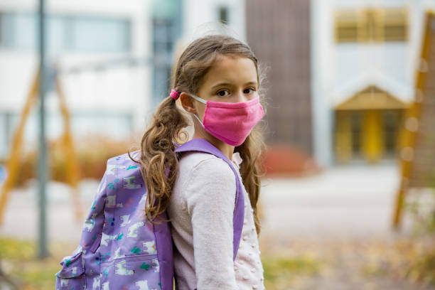istock Schoolgirl wearing protective fabric reusable face mask going to school 1277355694