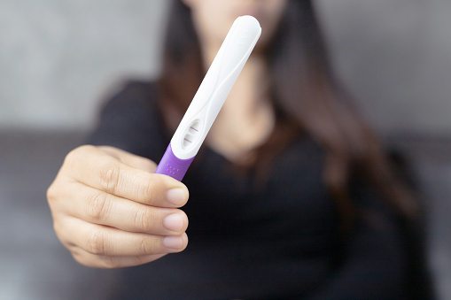 A woman carrying a pregnancy test with birth control pills