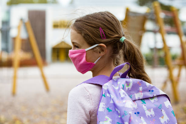 istock Schoolgirl wearing protective fabric reusable face mask going to school 1277356008