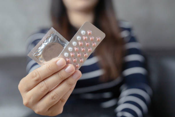 les femmes portent des pilules contraceptives et des préservatifs, hand focus. - contraceptive sex education birth control pill condom photos et images de collection