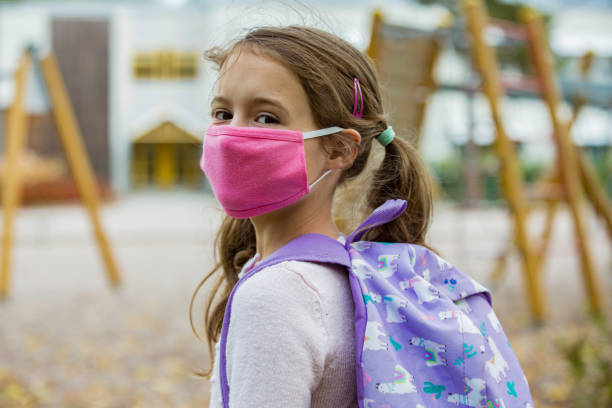 istock Schoolgirl wearing protective fabric reusable face mask going to school 1277356852