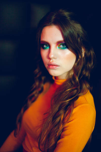 красивая молодая девушка с ярким цветом макияжа в оранжевой водолазке - green eyeshadow стоковые фото и изображения