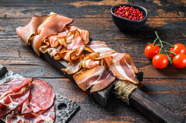 junta de antipasto de carne, pancetta, salami, jamón en rodajas, salchicha, prosciutto, tocino. fondo de madera oscura. vista superior - pancetta fotografías e imágenes de stock