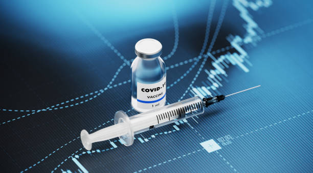 Vaksin COVID-19 dan jarum suntik duduk di atas latar belakang grafik keuangan biru. Fokus selektif. Komposisi horizontal dengan ruang salin. Vaksin COVID-19 dan Pasar saham dan konsep keuangan.