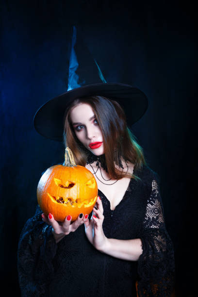 istock Happy Halloween . Halloween witch with a magic pumpkin on black background. 1277360190