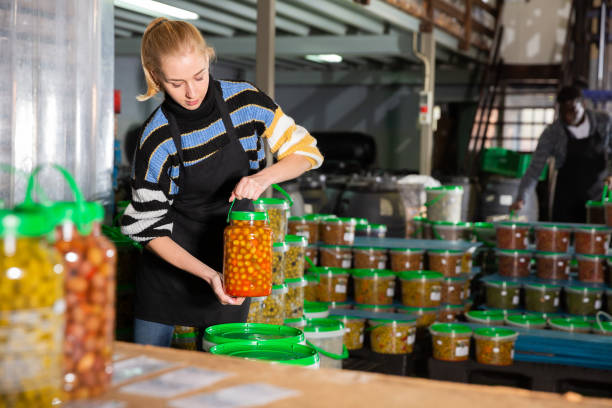 istock Female worker stocks plastic containers and cans with olives in warehouse 1277361558