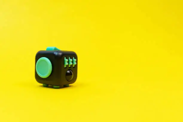 Photo of Black and green fidget cube on yellow background