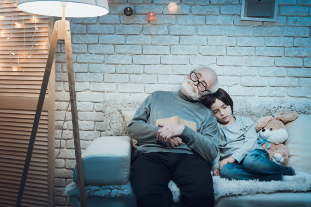 Grandfather and grandson are sleeping at home. The little grandson laid his head on grandfather and fell asleep. Grandfather with glasses fell asleep on the bed next to his grandson. sleeping grandpa stock pictures, royalty-free photos & images