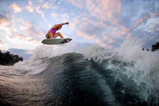 istock guy energetically jumps high above the wave on the surf style wakeboard. Summertime leisure 1277365831