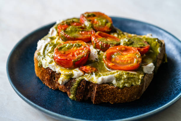 tartine toast santé avec truffe au fromage de cajou végétalien à la crème aromatisée, sauce pesto et tomates cerises. - appetizer bread breakfast cashew photos et images de collection